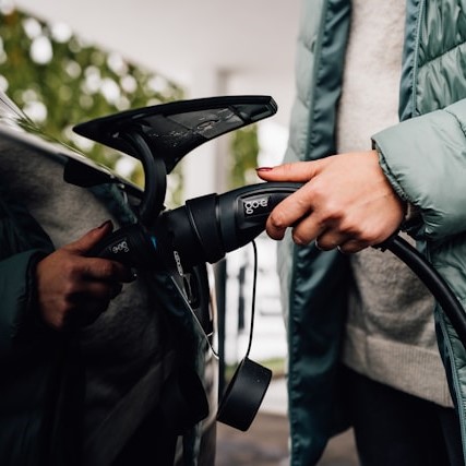 Close up of a womans hand holding a charger, charging her electric vehicle.